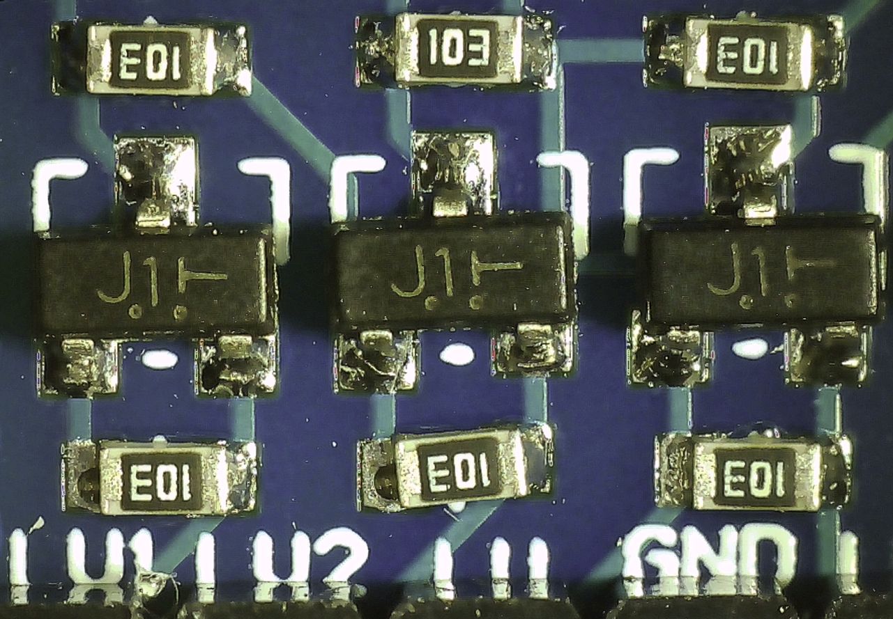 Micrograph showing closeup of BSS138 MOSFETs on the breakout board